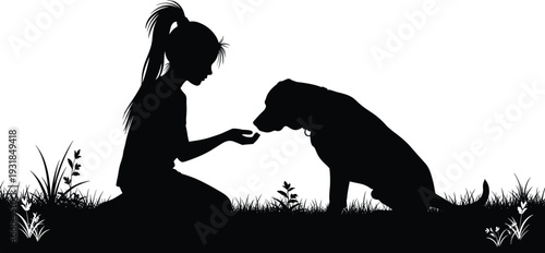Black silhouette of girl feeding dog in grass