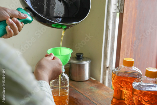 Φωτογραφία Selective focus on used cooking oil poured into plastic bottle using funnel by p