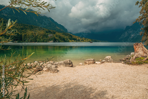 Peaceful alpine lake Bohinj surrounded by forested hills and looming storm clouds in Slovenia’s Triglav National Park.