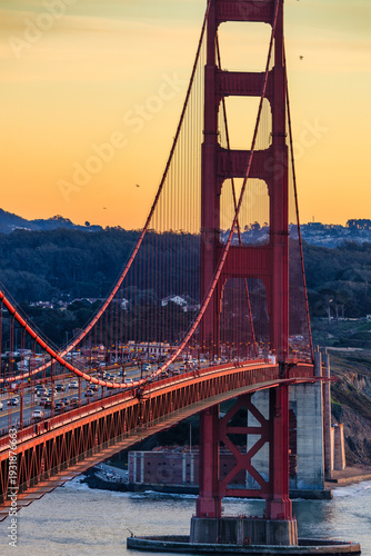 Golden Gate Bridge tower in San Francisco at sunset with evening traffic crossing the iconic red suspension bridge over the bay