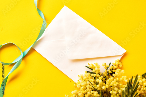 Mimosa fresh flowers on yellow background, frame with copy space on envelope,...