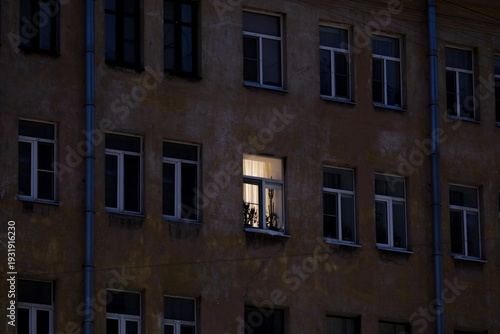 one illuminated window on the facade of an apartment building