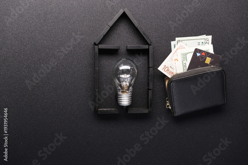 Real estate financing concept. Domino house with bulb, wallet, and credit card on black.