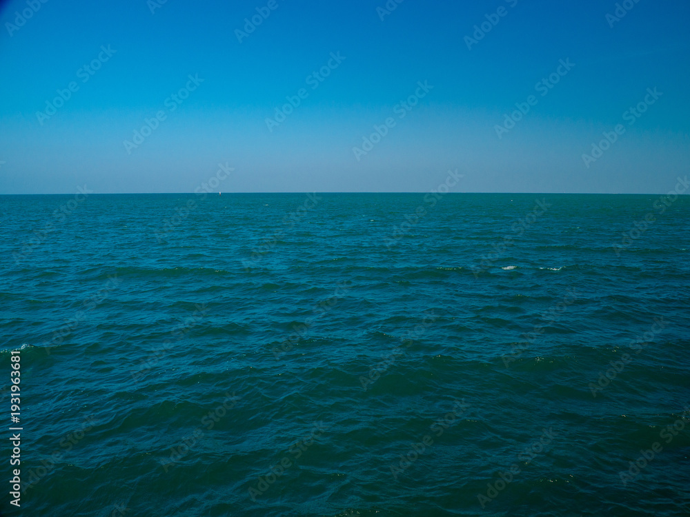Obraz premium Serene tropical beach with crystal clear turquoise water, gentle waves, and a bright blue sky with fluffy white clouds. peaceful and relaxing summer scene perfect for panorama and travel concepts.