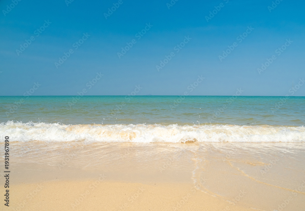 Fototapeta premium Peaceful panorama tropical sea beach with gentle waves rolling onto golden sand under bright blue sky with fluffy white clouds. relaxing summer scene perfect scene for travel holliday and nature lover