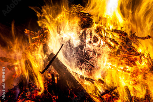 Wood burning in a large bonfire creating intense flames and light at night