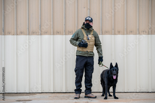 Quadro su tela An Immigration and Customs Enforcement (ICE) officer and a black German Shepherd conduct surveillance