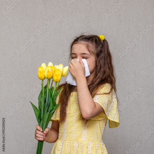 Konstfotografi Young girl sneezing from tulip pollen while holding yellow flower bouquet and ti