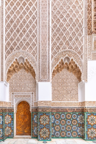 Exquisite Moorish architecture and symmetrical courtyard of the historic Ben Youssef Madrasa in Marrakech, Morocco, featuring intricate zellij tilework and carved cedar wood details