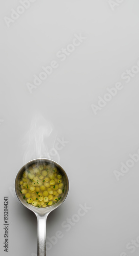 Metal ladle filled with simple split pea soup resting on the lower left edge of a large pale gray background, most of the space left empty as negative space for nutrition or budget cooking text.
