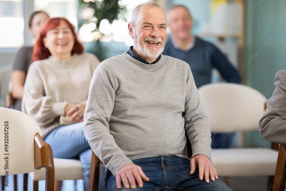 Naklejka premium Portrait of a laughing elderly man at a lecture among other elderly people