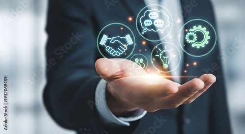 Hand holding digital icons representing business concepts like partnership, communication, and innovation