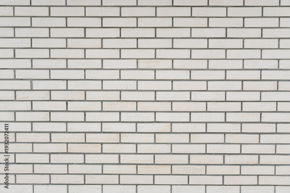 Fototapeta premium White brick wall with gray grout lines in a modern interior setting