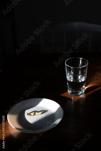 Pills on a white plate with a glass of water on a wooden table