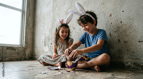 Two children in bunny ears enjoying chocolate Easter egg