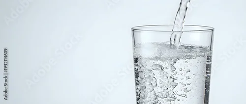 Panel kuchenny z motywem Clear water being poured into transparent glass with bubbles and splash, refreshing drink concept for health and hydration lifestyle on white background.