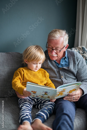 Joyful Grandfather and Child Reading Together: Cozy Family Bonding in Living Room