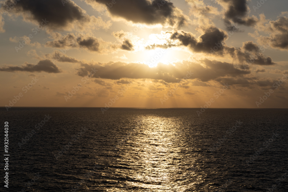 Fototapeta premium Golden Sunrise Over the Caribbean Sea with Dramatic Sun Rays and Ocean Reflection