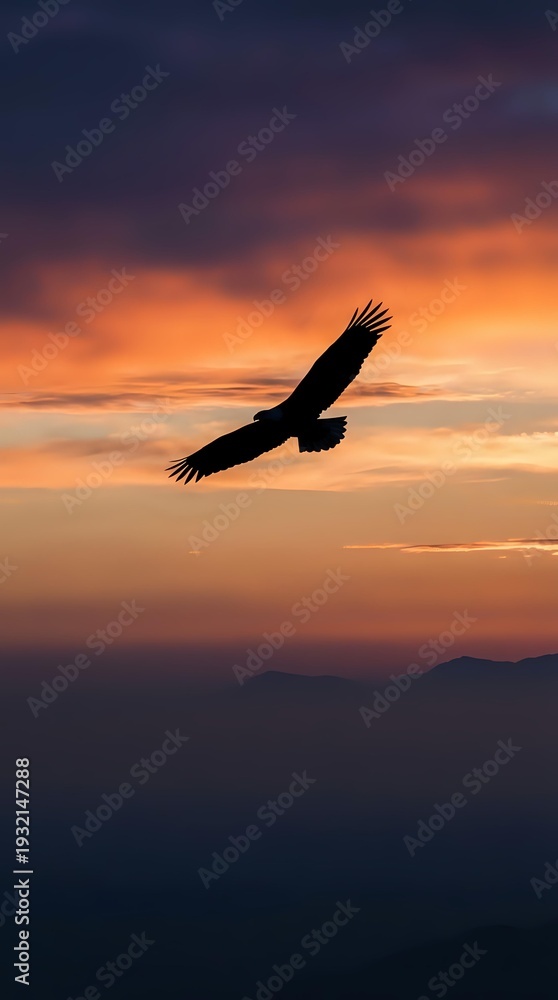 Fototapeta premium Majestic eagle soaring through dramatic sunset sky with vibrant orange and purple clouds over mountain silhouettes creating inspiring freedom concept.