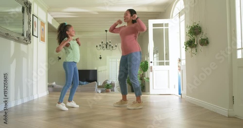 Mother and preteen daughter practicing dance, mother leading while daughter mirrors on wood floor