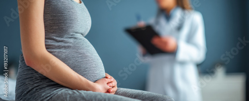 Pregnant woman sitting on bed, hands resting on her belly, while healthcare professional takes notes in background. scene conveys sense of care and anticipation
