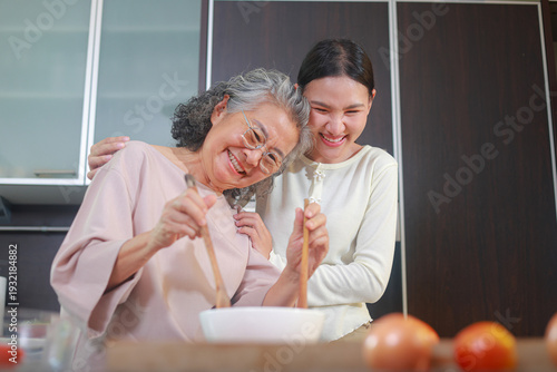 Foto An elderly mother and her Asian daughter are happily cooking together