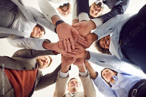 Bild auf Leinwand Close up bottom view photo of diverse business people putting their arms together