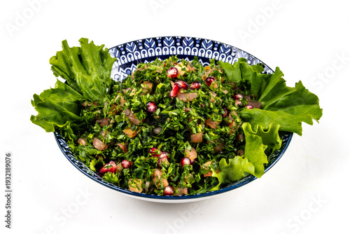 A dish of Tabbouleh, a Lebanese salad made from crisp lettuce, diced tomatoes, parsley, pomegranate seeds, and herbs mixed with toasted pita pieces isolated on white.