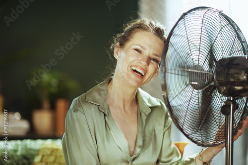 Photography A woman with an open-mouthed laugh revels in the cool breeze from a standing fan, her face reflecting pure joy and comfort