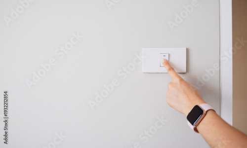 Photos Close-up of a hand turning off light switch on wall