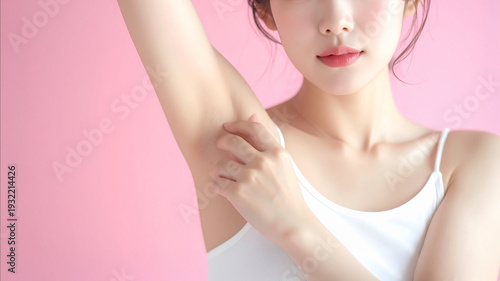 ピンク背景で脱毛後の脇を見せる若い女性のクローズアップ　ボディケア・美容イメージ