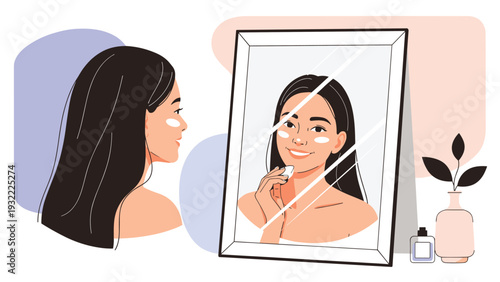 Young woman looking into a rectangular tabletop mirror while applying cream or makeup to her face in a soft minimalist room setting.