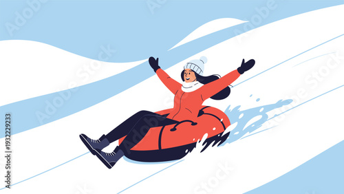 Cheerful woman in winter clothes enjoys the thrill of snow tubing as she slides down a snowy hill with her arms raised in joy.