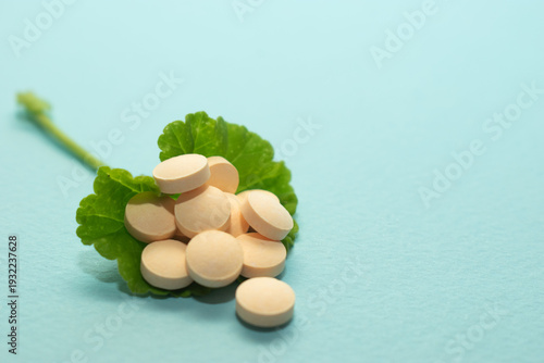 Minimal healthcare concept with pills and green leaves on blue background