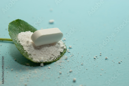 Minimal healthcare concept with pills and green leaves on blue background