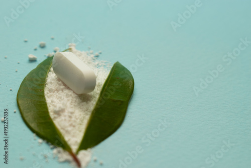 Minimal healthcare concept with pills and green leaves on blue background