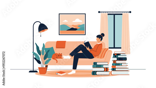 Young woman sitting comfortably on a peach colored sofa while reading a book and relaxing with her ginger cat in a cozy living room.