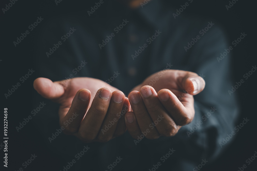 Obraz premium Close-up of cupped hands with fingers outstretched against a dark background.