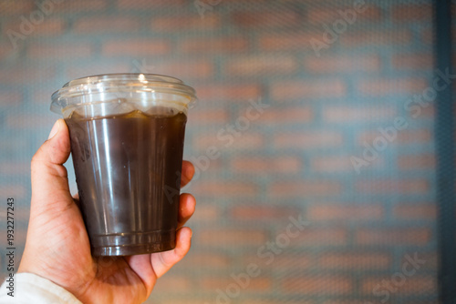 Wallpaper Mural Close up hand holding Iced black Americano in take away plastic cup Torontodigital.ca