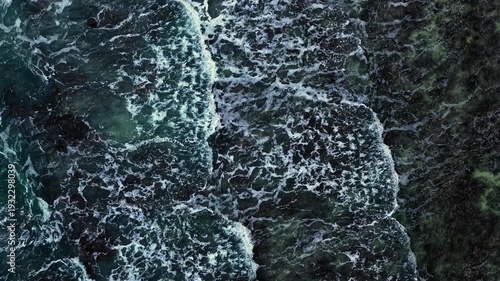 Aerial Drone Pullback Shot of Ocean Waves Crashing on Rocky Coastline, Top Down View