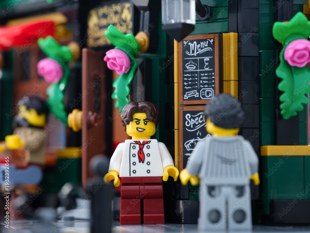 Naklejka premium Tambov, Russian Federation - June 24, 2025 Lego waiter and customer minifigures standing outdoors near a cafe.
