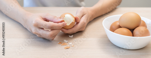 Tableau sur toile Protein in food, keto diet asian young woman hand peeling, shelling chicken boiled egg, prepares ingredient for breakfast meal on table at home