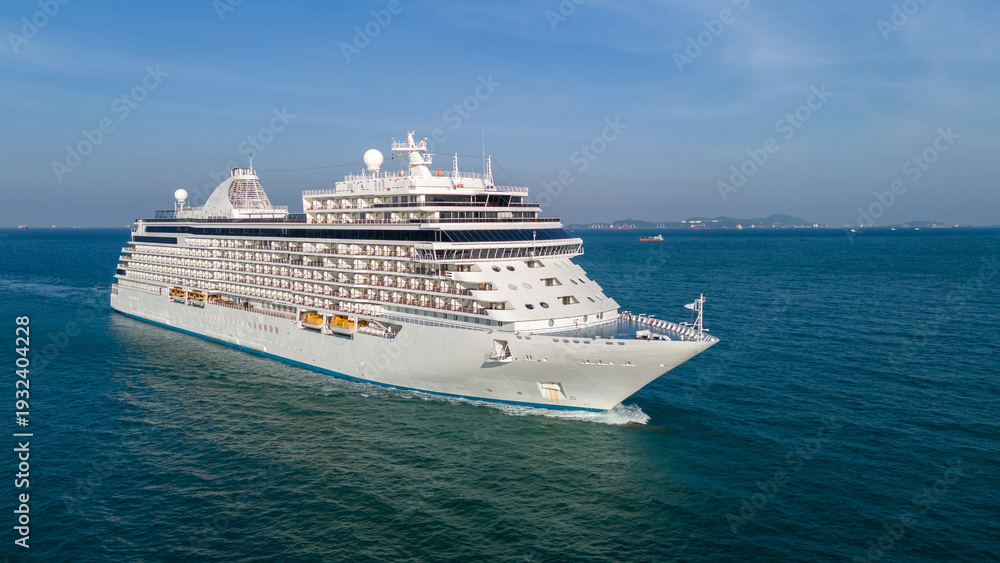 Fototapeta premium Majestic white luxury cruise ship sailing across the deep blue ocean water on a bright sunny day. Summer vacation, tropical travel destination, and global tourism industry concept.
