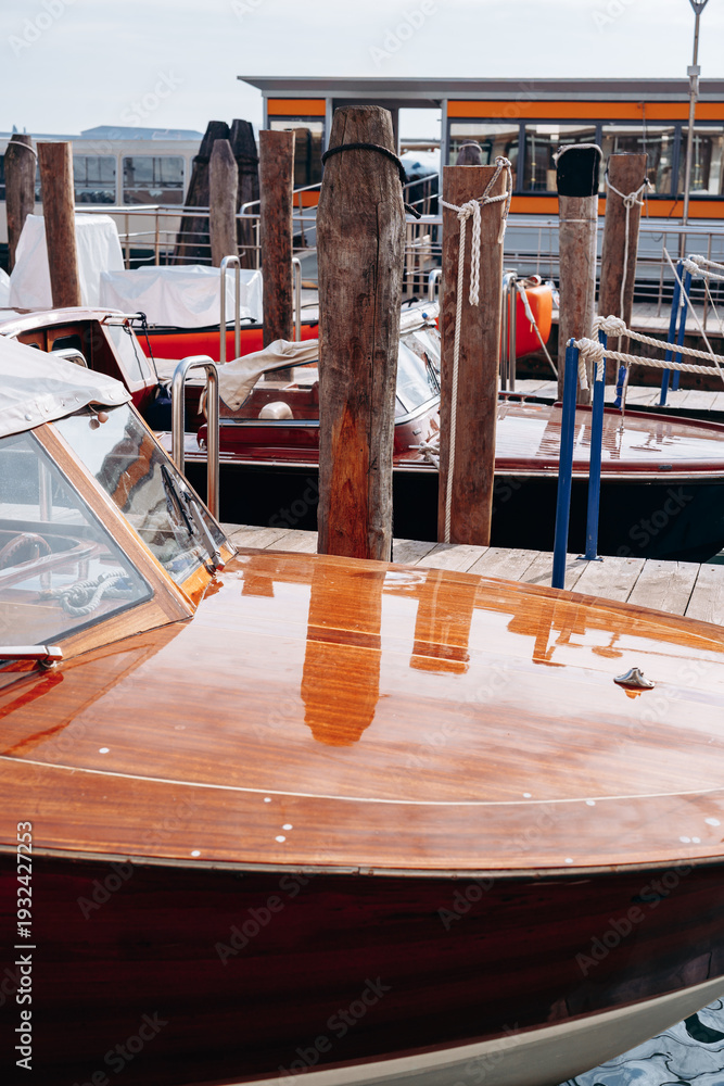 Fototapeta premium Wooden boats docked at a marina with reflections in the water on a sunny day