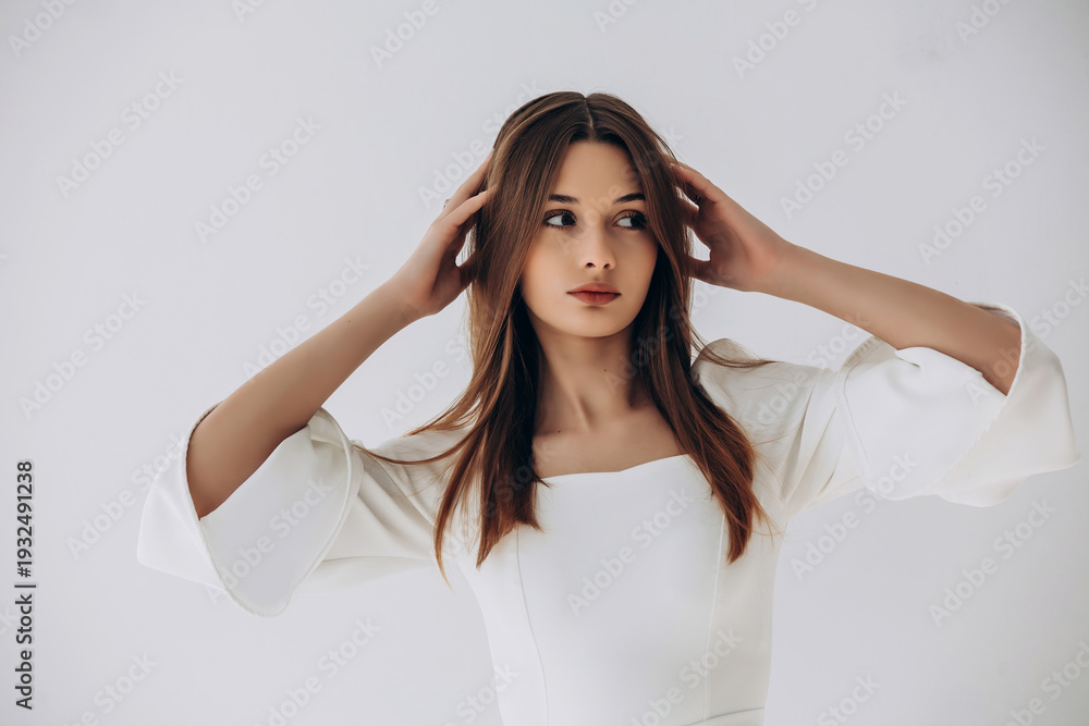 Naklejka premium Beauty portrait of a model, a beautiful brunette girl with straight long hair in a white dress, healthy and natural on a white background