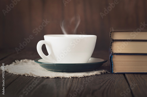 Cup of hot tea with heart shaped steam and stack of books on rustic wooden table, cozy reading concept
