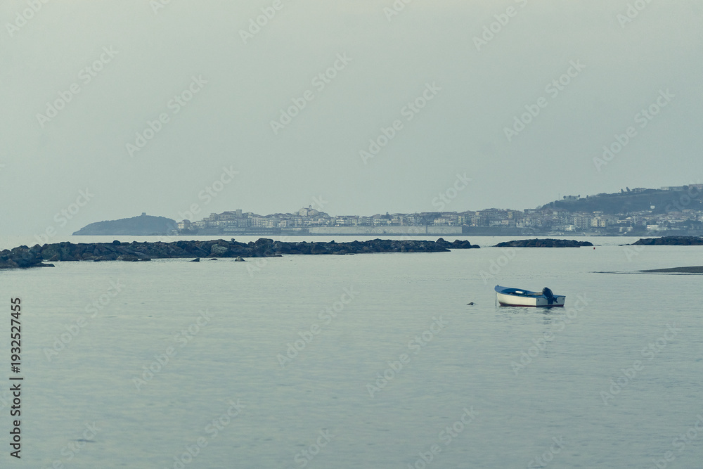 Obraz premium Small boat floating on calm bay waters