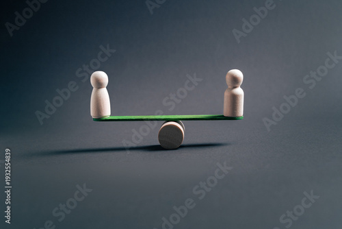 Business equilibrium concept with two wooden figures balancing on seesaw