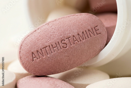 Closeup of antihistamine tablet in white container with pills  