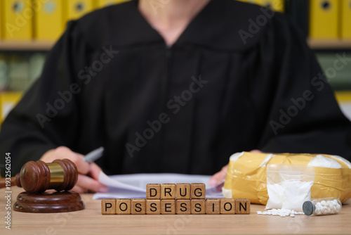 Obraz na plátně In a solemn courtroom setting, a judge in black robes reviews paperwork marked by drug evidence